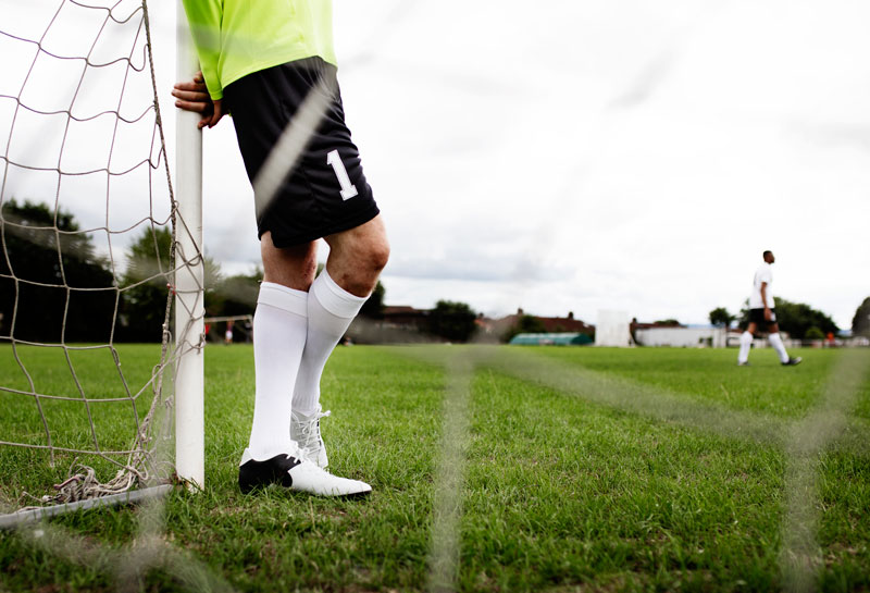 brankár opierajúci sa o futbalovú bránku